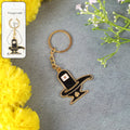 Golden Shivling keychain in metal with intricate design on plain background