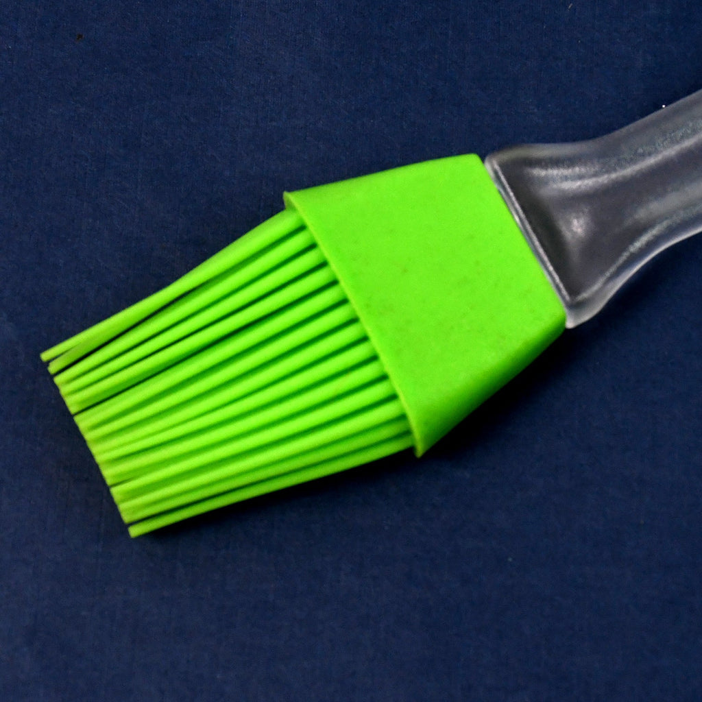 Silicone pastry brush basting oil on a baking tray, ideal for even coating.